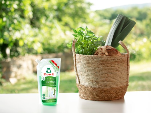 A Frosch bio-spirit glass cleaner refill pouch stands next to a shopping basket.