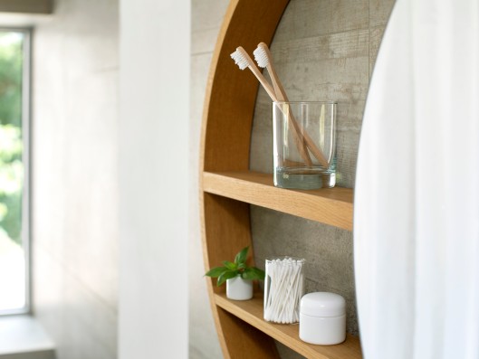 Mirrored cabinet with toothbrushes and hygiene products next to a window